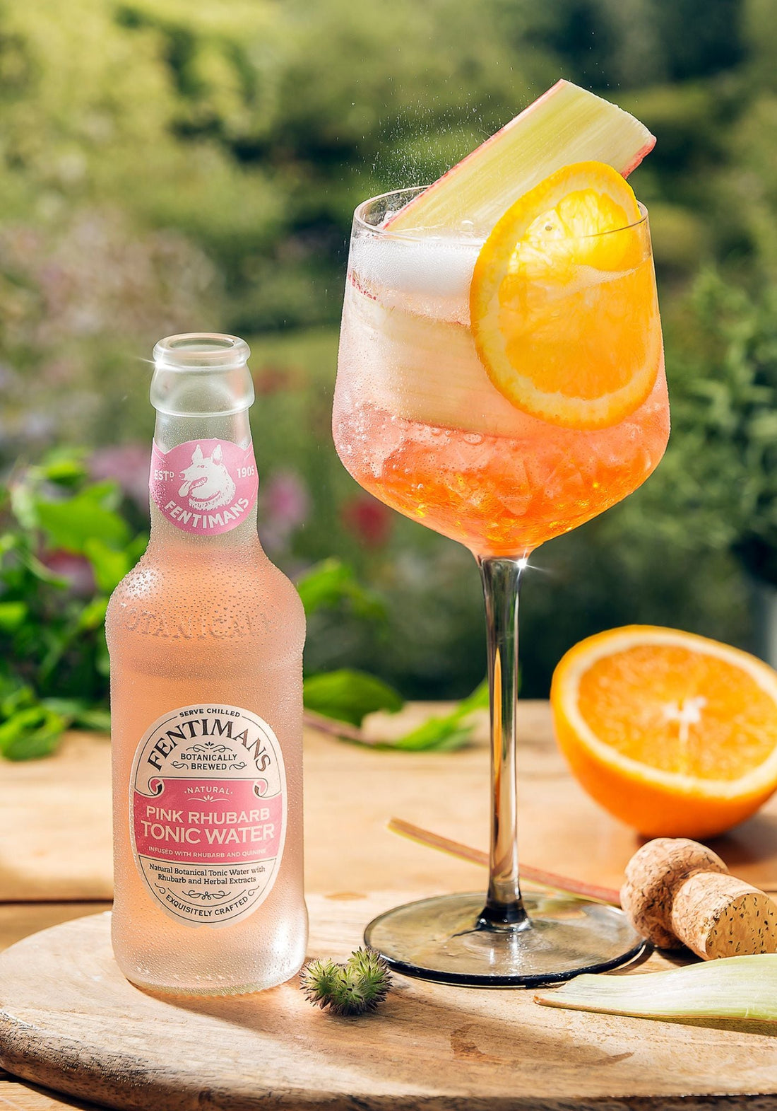 A bottle of Fentimans Pink Rhubarb Tonic Water beside an Aperol serve garnished with rhubarb and orange