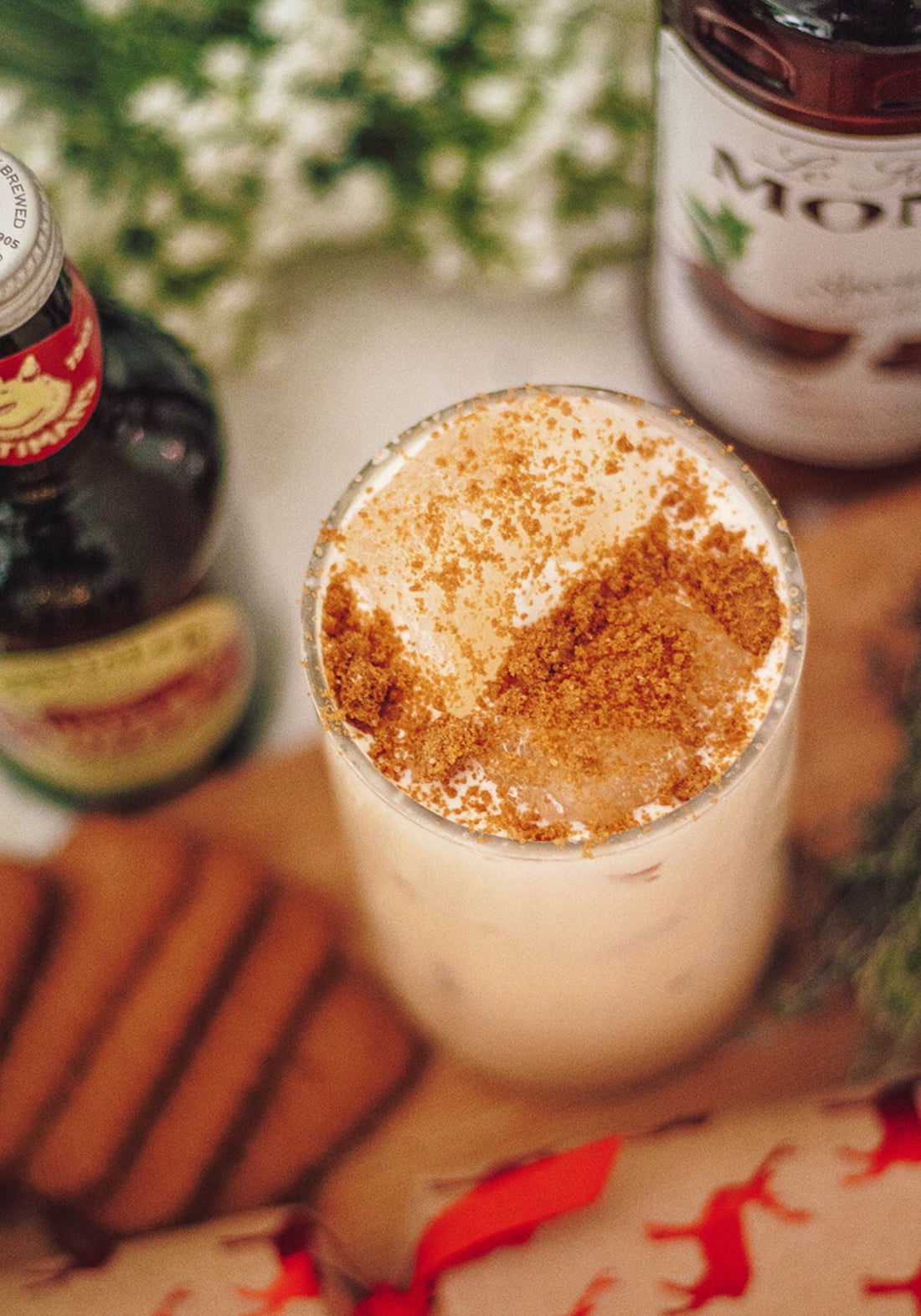 A short glass of a creamy eggnog cocktail garnished in biscuit and placed beside a bottle of Fentimans Ginger Beer